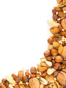 Background of mixed nuts - hazelnuts, almonds, walnuts, pistachios, peanuts, pine nuts peeled and not peeled - vertical with copy space. Isolated one edge. Top view or flat lay