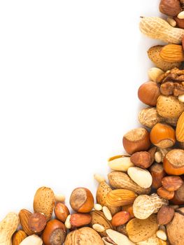 Background of mixed nuts - hazelnuts, almonds, walnuts, pistachios, peanuts, pine nuts peeled and not peeled - vertical with copy space. Isolated one edge. Top view or flat lay