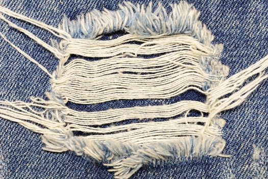 A closeup picture of a part of the jeans that is a bit torn for fashion background