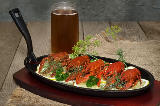 Boiled crawfish with lemon,herbs and beer. In a cast iron skillet and an old wooden background