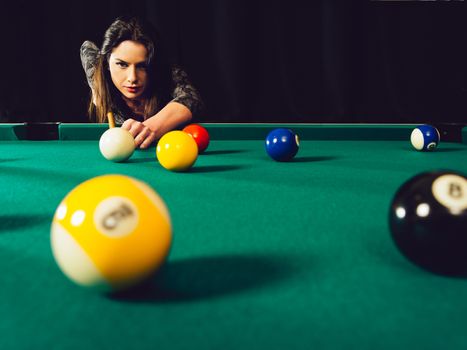 Photo of a beautiful woman leaning over a pool table playing pool.