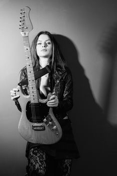 Photo of a sexy brunette woman standing and holding an electric guitar.
