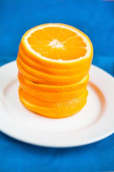 Tower of sliced of an orange on a white plate on a blue background