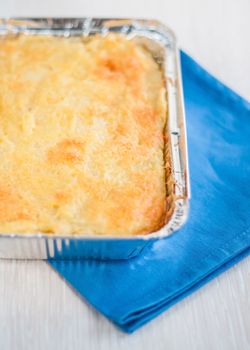 casserole in a disposable form of foil on a blue napkin