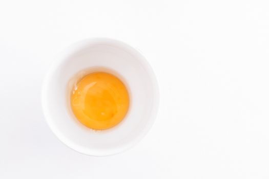 raw egg yolk in a bowl on a white background.