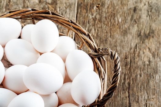 Chicken eggs in the basket on wooden background.