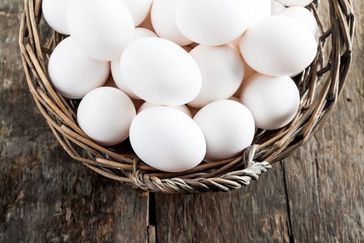 Chicken eggs in the basket on wooden background.