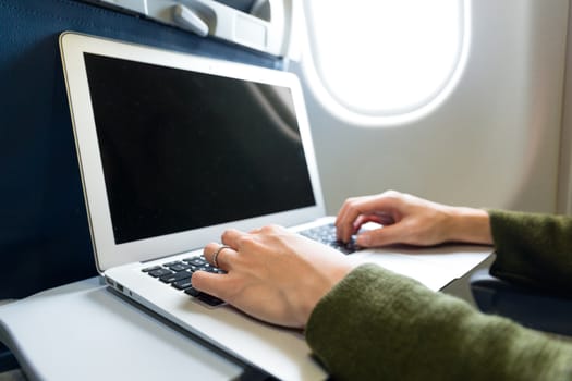 Woman working on laptop computer on board of an airplane