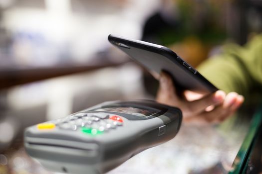 Woman paying with NFC technology on cellphone