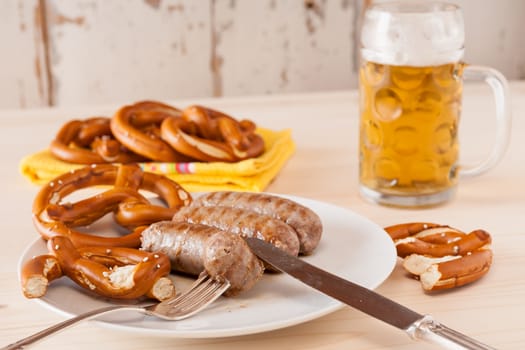 Bavarian cooked sausage and pretzel on background with a glass of beer