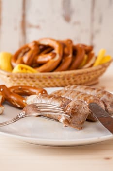 Closeup of bavarian cooked sausage and pretzel on a breadbasket on background