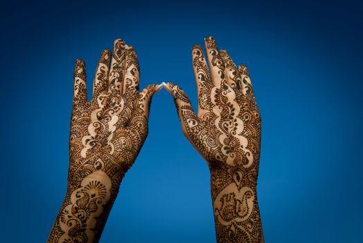 Image of Henna Tattoo's on an Indian bride's hands reaching to the sky