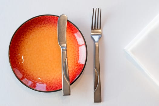 Starter meal setup with red hot plate and white napkin decoration. Selective focus.