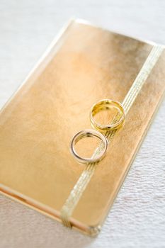 Wedding rings on golden book of memory, selective focus