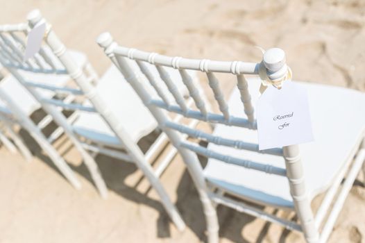 Chairs set up on white sand for beach wedding, reserved, selective focus