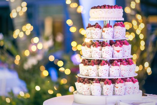 Sweet wedding cake made from fresh berry cupcake with bokeh background.