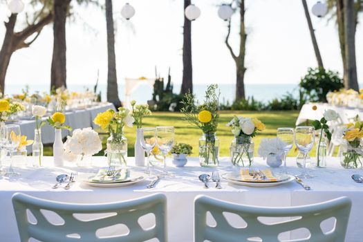 Elegance table set up white, green and yellow flowers theme, selective focus.