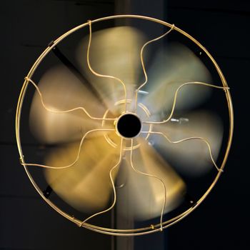 Close up brass ceiling fan on black wooden background.