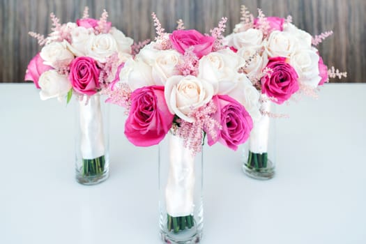 Mixed white & pink roses bouquets on white table, wooden background. Selective focus.