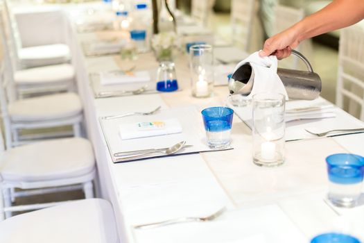 Woman pouring water from stanless jar to a glass