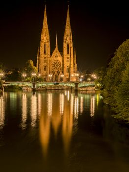 Strasbourg, France night photography with the beautiful St. Paul church with its two majestic towers and their water reflection