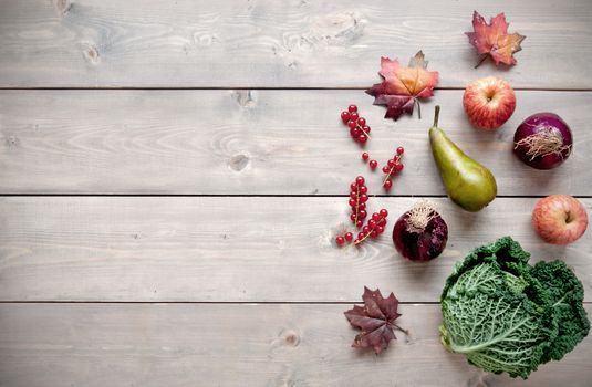Selection of natural autumn produce over a wooden background with space