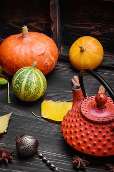 Warming autumn tea and teapot on background of pumpkin