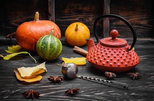 Warming autumn tea and teapot on background of pumpkin