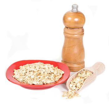 red dish  with oats flakes pile on white background.