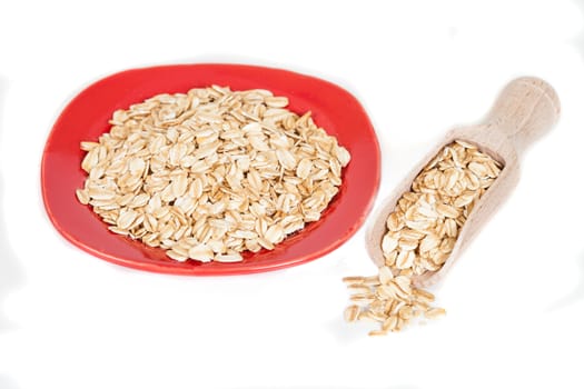 red dish  with oats flakes pile on white background.