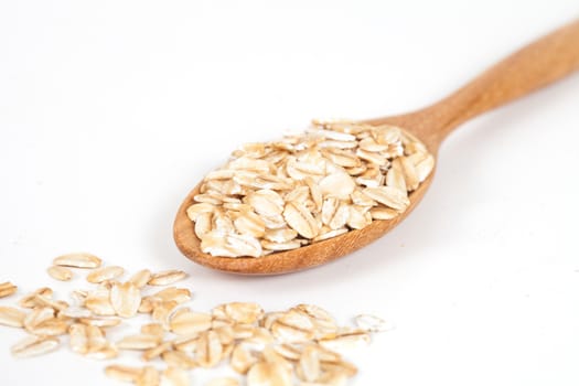 Oats flakes pile in wood spoon on white background