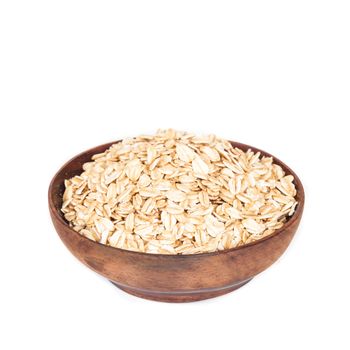 Wooden bowl with oats flakes pile on white background.