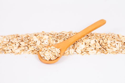 Oats flakes pile in wood spoon on white background