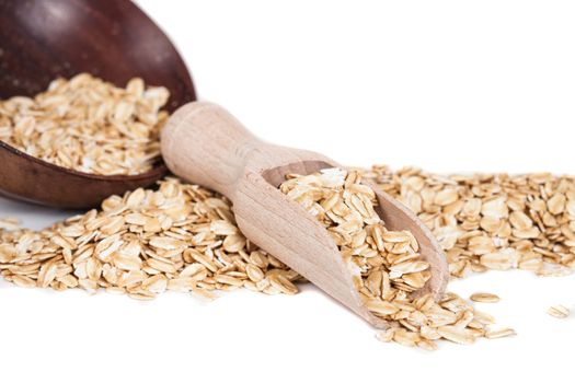 Oats flakes pile in wood spoon on white background