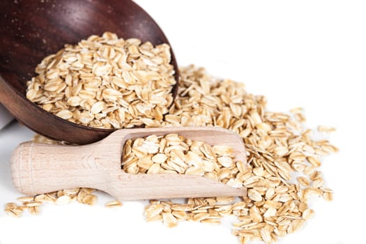 Oats flakes pile in wood spoon on white background