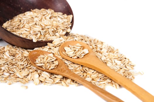 Oats flakes pile in wood spoon on white background