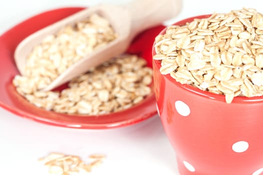 red cup with oats flakes pile on white background.