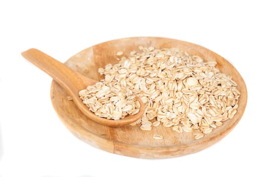 dish and wood spoon with oats flakes pile