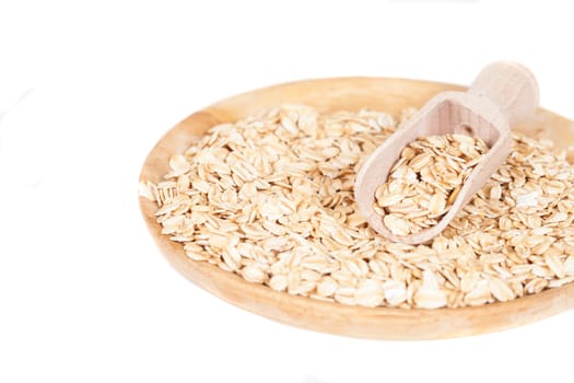 dish and wood spoon with oats flakes pile