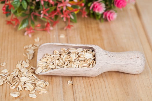  wood spoon with oats flakes pile on wood 
background.
