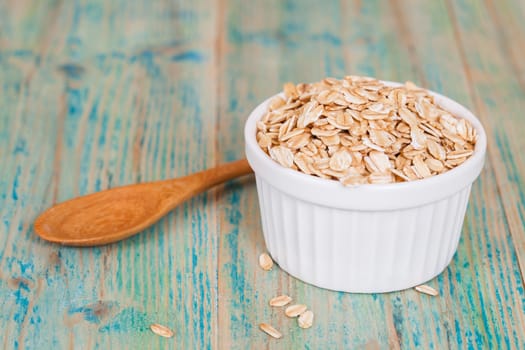 oats flakes pile in bowl on wood background.