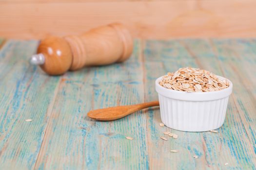 oats flakes pile in bowl on wood background.