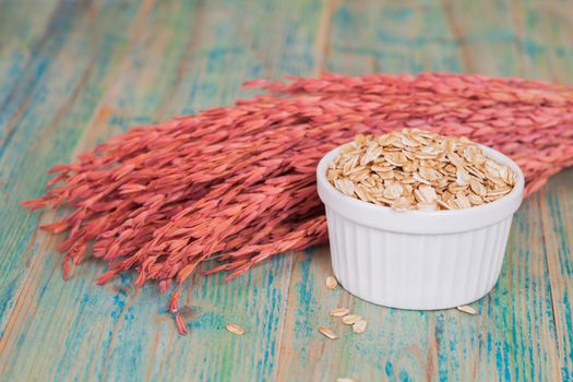 oats flakes pile in bowl on wood background.