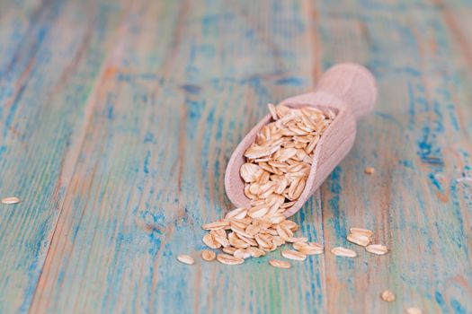 wood spoon with oats flakes pile on wood 
background.