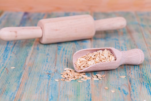 wood spoon with oats flakes pile on wood 
background.