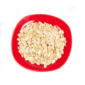 red dish  with oats flakes pile on white background.