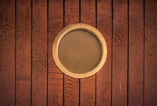 Background with a wall made of wooden planks and a small round window in the middle.