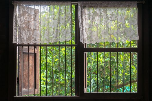 Old style Thai window with top-half lace curtain.