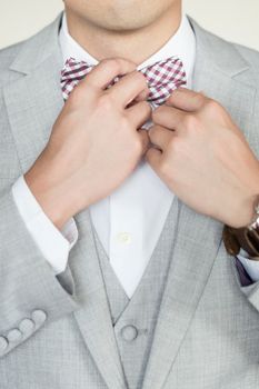 Man in gray striped jacket adjusting bow tie. Closeup.