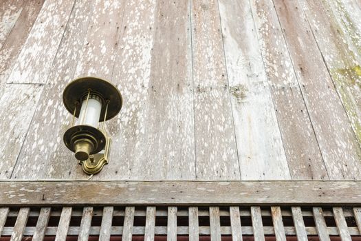 The old style lantern hang on old wooden wall.